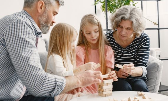 A family enjoying time together playing a block stacking game in their living room.